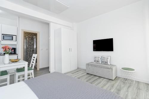 a white room with a bed and a couch and a desk at Studio Apartments Nada in Umag