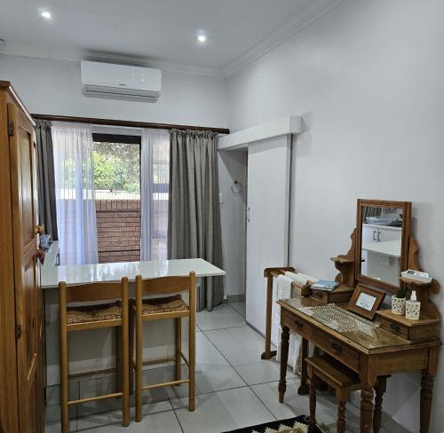 a room with a table and a desk and a table and a window at Flamebreeze Corner @ Supertubes Jeffreys Bay in Jeffreys Bay