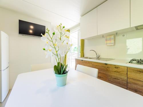 a white kitchen with a vase with flowers on a table at Campeggio Internazionale Madonna del Ghisallo in Magreglio