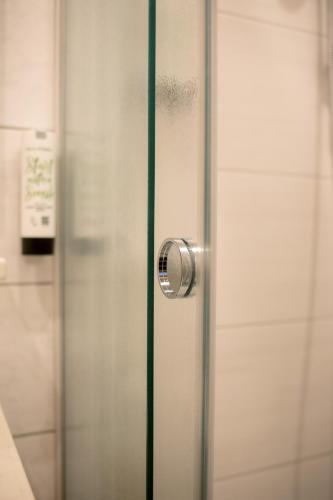 a shower with a glass door with a handle at Hotel Gabriel in Keutschach am See