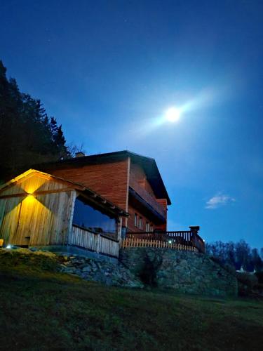 a house with the moon in the sky behind it at Chata POD HOUBOVÝM VRCHEM 2 in Horní Planá