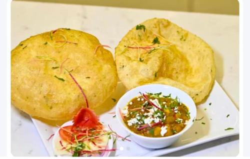 a plate of food with potatoes and a bowl of soup at Hotel Airport Suites Suitable for Hourly Bookings in Lucknow