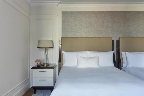 a bedroom with a large white bed and a lamp at Waldorf Astoria Amsterdam in Amsterdam