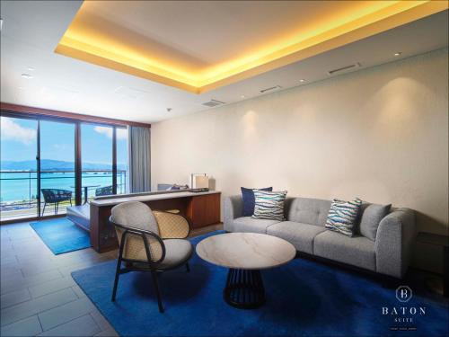 a living room with a couch and a table and chairs at BATON SUITE Okinawa-kourijima in Nakijin