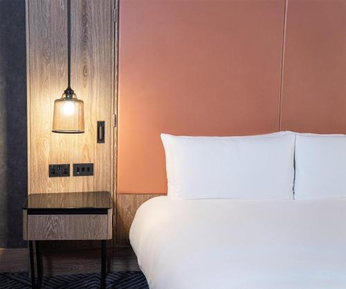 a bedroom with a white bed and a lamp at Hilton London Bankside in London