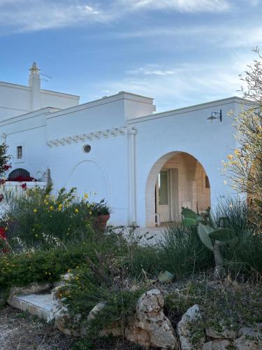 a white building with an archway in a garden at B&B Lamascopone in Fasano