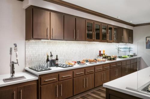 a kitchen with wooden cabinets and a buffet of food at Homewood Suites By Hilton San Jose Santa Clara in San Jose