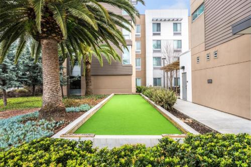 a green lawn in front of a building with a palm tree at Homewood Suites By Hilton San Jose Santa Clara in San Jose