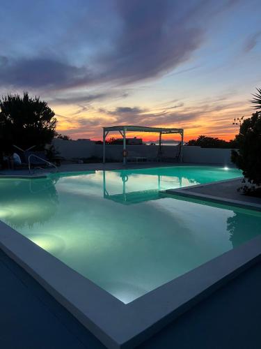 a large swimming pool with a playground at sunset at Santo Margarita in Oia