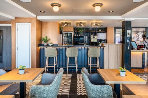 a restaurant with two tables and chairs and a bar at Point A Hotel London Canary Wharf in London