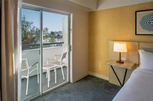 a bedroom with a balcony with a bed and a table and chairs at Hilton Garden Inn Dana Point Doheny Beach in Dana Point