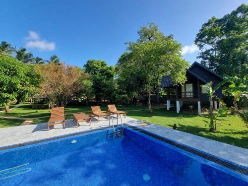 une piscine avec des chaises et une maison dans l'établissement Liyon Rest sigiriya, à Sigirîya