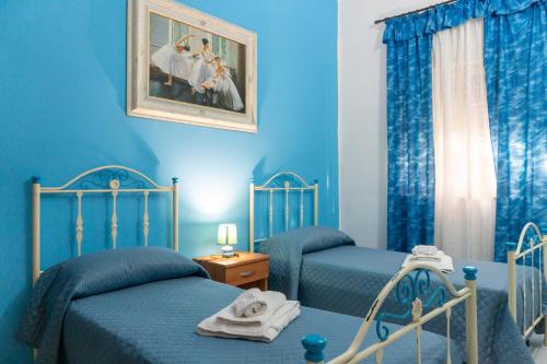 a blue bedroom with two beds and a picture on the wall at Casa Vacanze Il Sole in Casamassella
