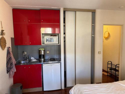 une petite cuisine avec des placards rouges et un four micro-ondes dans l'établissement Studio cosy Cannes centre, à Cannes