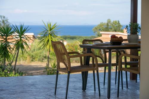 ein Tisch und Stühle auf einer Terrasse mit Blick auf das Meer in der Unterkunft Aluna Boutique Suites in Vasilikos