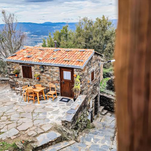 una pequeña casa de piedra con mesa y sillas en Refúgio do Casal, en Lousã