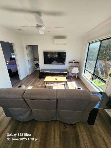 a living room with a large couch and a tv at Suburban Paradise With a Pool in Petrie