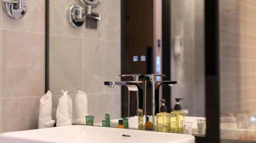 a bathroom sink with a large mirror and a sink at 沃德酒店济南经十东路融创文旅城店 in Jinan