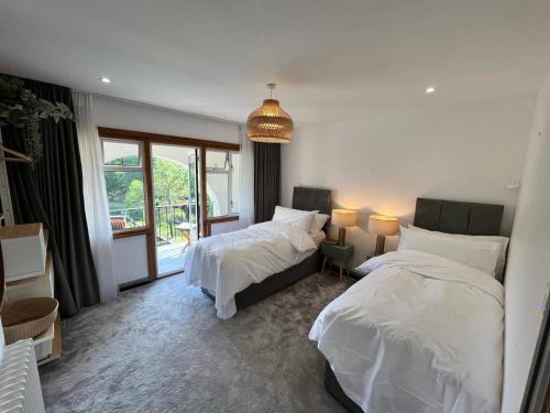 a bedroom with two beds and a large window at 5 Bedroom Lake House in a nature reserve in Devizes