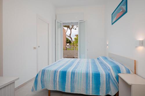 a white bedroom with a bed with a blue comforter at Hotel Flora in Cesenatico