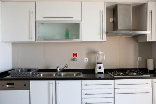 a kitchen with white cabinets and a sink and a blender at Moradia Garcês in Santa Cruz