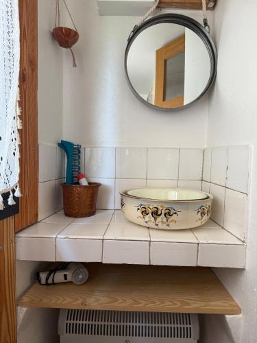 - une salle de bains avec un bol sur une étagère et un miroir dans l'établissement YouMe, petit nid douillet, à Aumessas