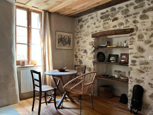a dining room with a table and chairs and a window at YouMe, petit nid douillet in Aumessas