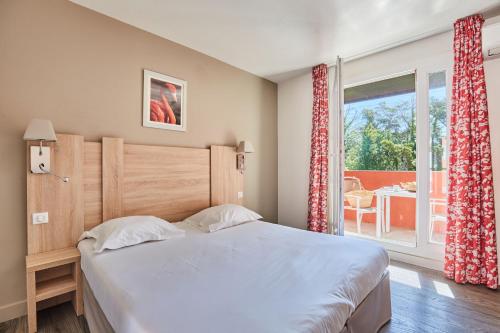 une chambre avec un lit et une grande fenêtre dans l'établissement Résidence Odalys Le Village Camarguais Les Gardians, à Arles