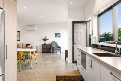 a kitchen with white cabinets and a dining room at 120m to Wainui Beach - Modern Coastal Unit in Gisborne