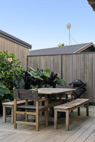 a picnic table and two benches on a patio at 120m to Wainui Beach - Modern Coastal Unit in Gisborne