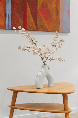 a table with a vase with flowers in it at 120m to Wainui Beach - Modern Coastal Unit in Gisborne