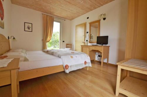 Dormitorio con cama, escritorio y TV en Agriturismo Locanda de l'Arguta, en Trento