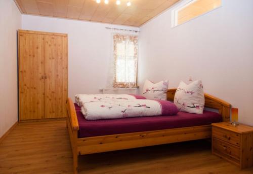 a bedroom with a wooden bed and a window at Geigerbauernhof in Mühlenbach