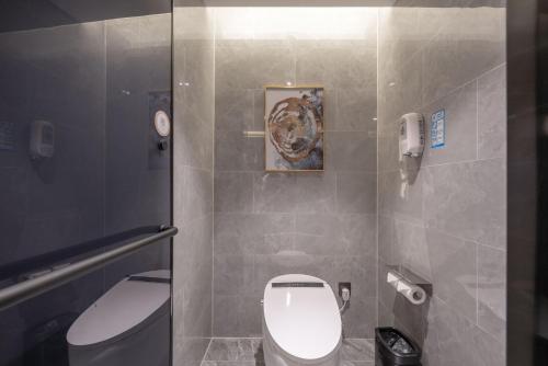 a bathroom with a toilet and a picture on the wall at 沃德酒店济南经十东路融创文旅城店 in Jinan