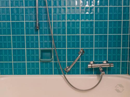 a bath tub with a hose attached to a blue tiled wall at Enri Theater und Pension Bruderhaus in Altensteig