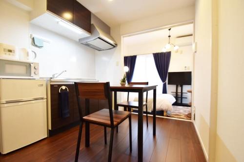 a small kitchen with a table in a small apartment at enジョイまーるひろ 401 in Naha