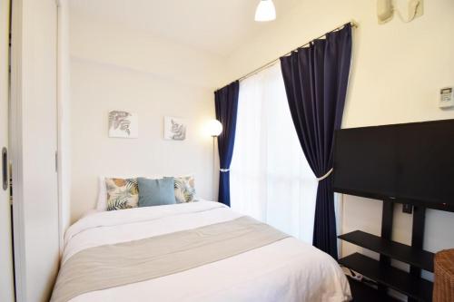 a bedroom with a bed and a window at enジョイまーるひろ 401 in Naha