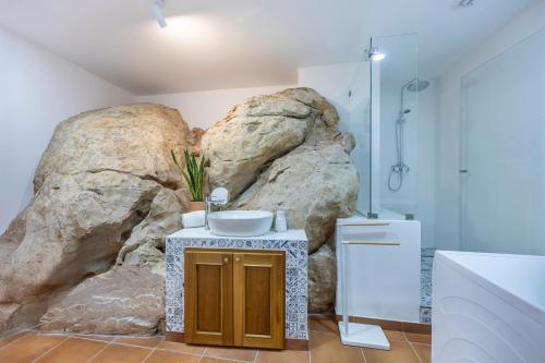 a bathroom with a sink and a large rock wall at Salema Family Home in Salema