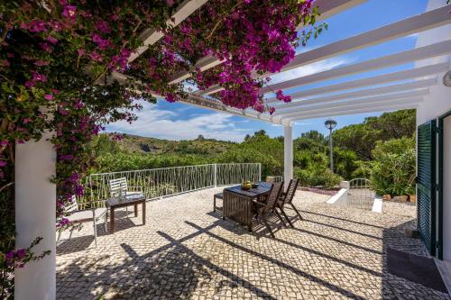 a patio with a table and chairs and flowers at Salema Family Home in Salema