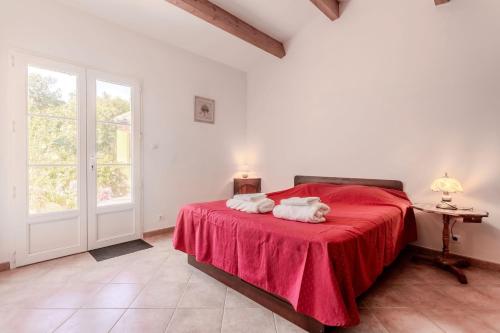 a bedroom with a red bed with two towels on it at Maison d'hôtes Collobrières in Collobrières