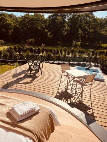 - une terrasse en bois avec une table et des chaises à côté de la piscine dans l'établissement Domaine de Chabrague, à Amou