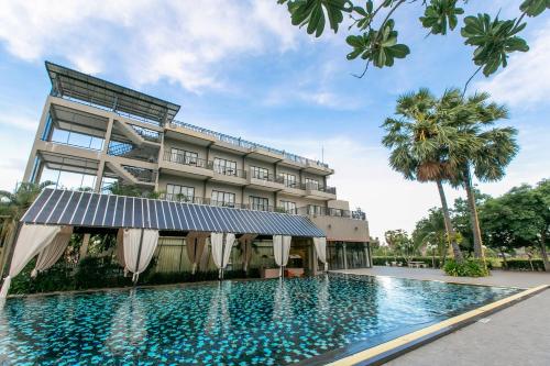 a hotel with a swimming pool in front of a building at Baan Phing Phu Praew Cha-Am Resort บ้านพิงภูแพรว รีสอร์ท ชะอำ in Cha Am