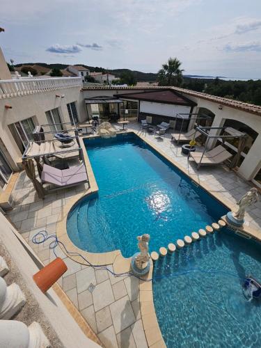une grande piscine avec des chaises et un bâtiment dans l'établissement La Pinède D'Estarac, à Bages
