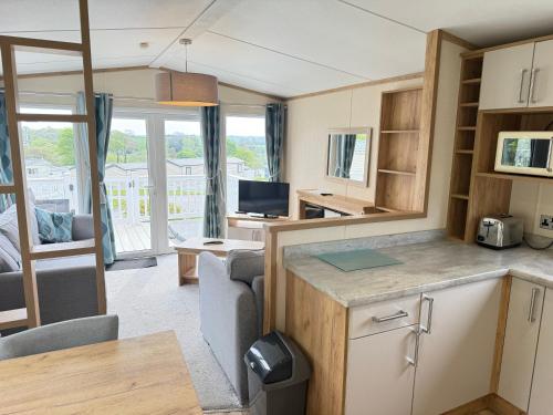 a caravan kitchen and living room with a couch and a tv at Rural Retreat Chy Kensa a Hot Tub Haven in Grampound