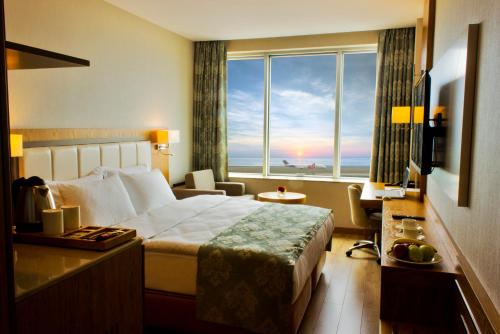 トラブゾンにあるYildiz Life Hotelのベッドと大きな窓が備わるホテルルームです。