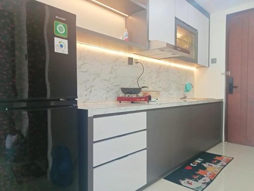 a kitchen with a black refrigerator and white cabinets at Apartement 2 Bedroom And 1 Living Room A22701 Pollux Habibi Batam Centre in Batam Center