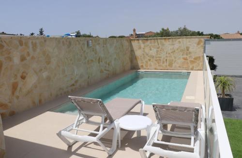 a patio with two chairs and a swimming pool at Casa el rincon de la Rosa II in Conil de la Frontera