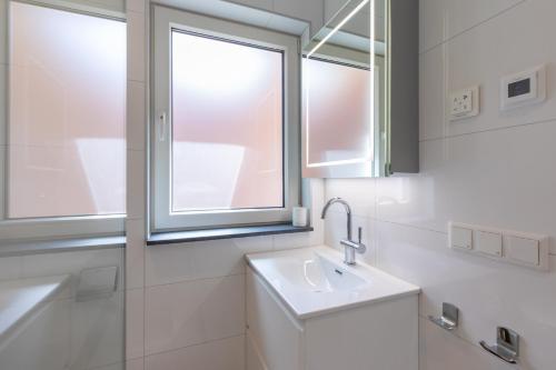a white bathroom with a sink and a window at Vakantiehuis Westkapelle dichtbij strand in centrum in Westkapelle