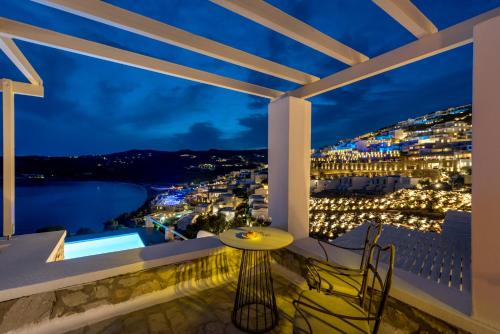 a balcony with a view of a city at night at Cova Mykonos Suites in Elia Beach