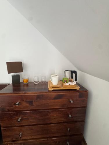 a wooden dresser with cups and a lamp on it at Bieszczadzki Dworek Polanczyk in Polańczyk